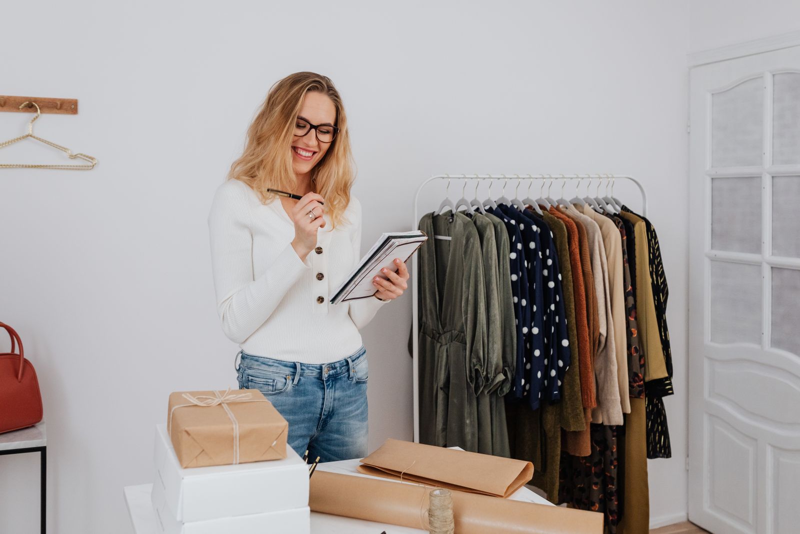 A boutique owner smiling while taking inventory notes among the racks