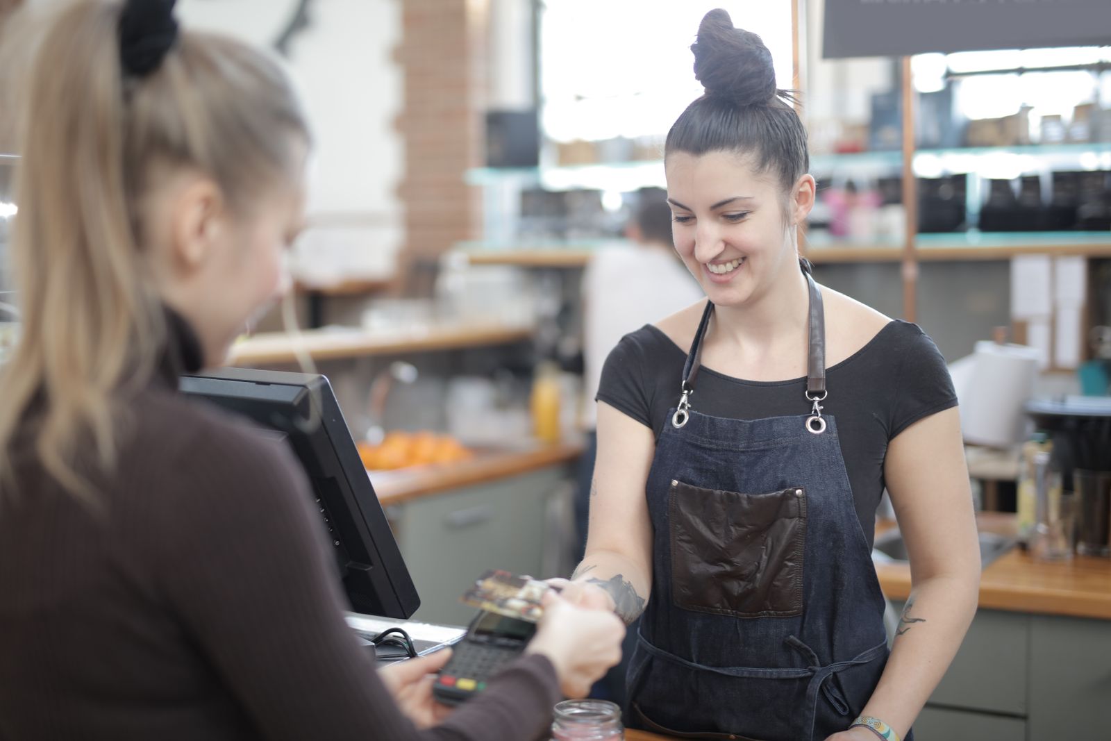 A smiling cashier taking a card payment at a modern store counter