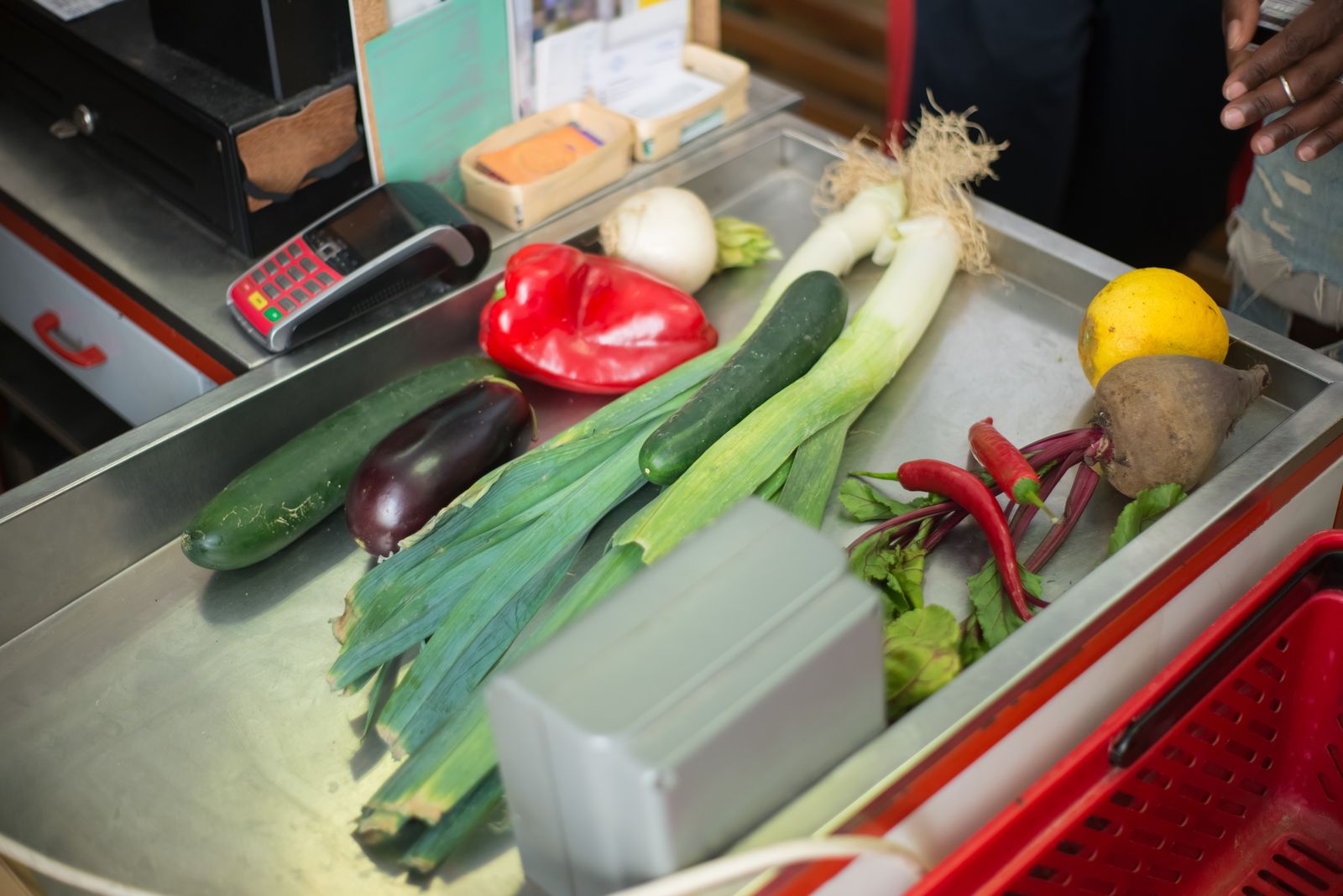Fresh vegetables on a grocery checkout counter beside the register