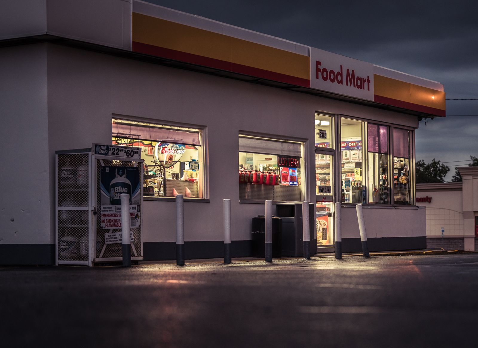A Food Mart convenience store lit up at night beside its gas pumps