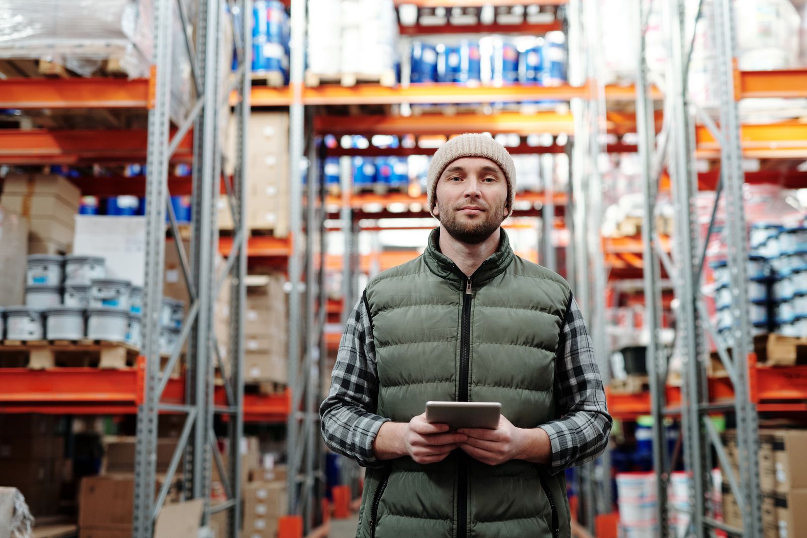 A warehouse worker holding a tablet in a stocked aisle