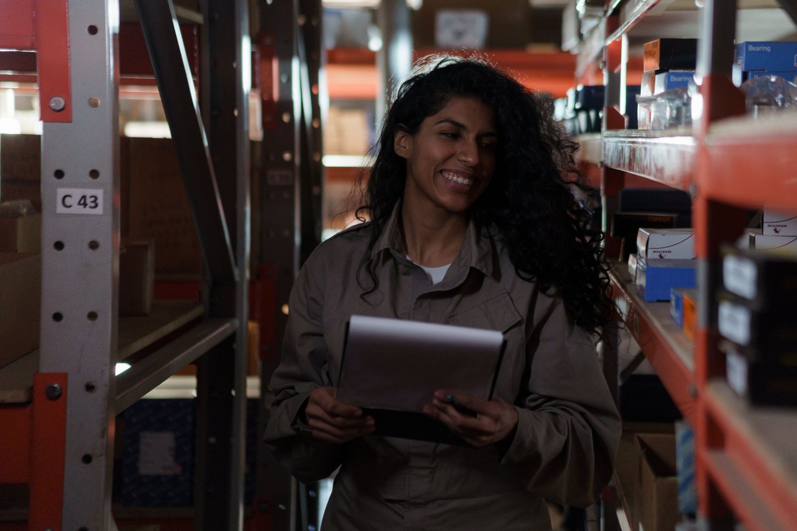 A smiling worker checking inventory on a tablet between shelves