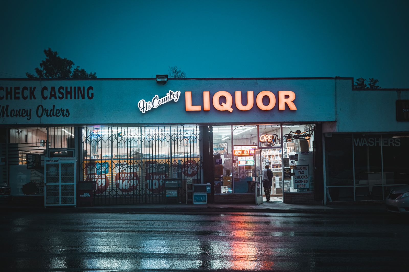 A neon lit liquor store on a rainy evening