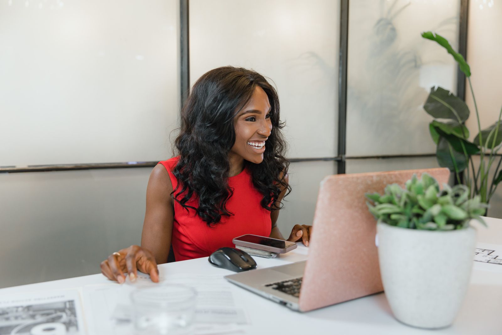 A smiling business owner at a laptop and phone
