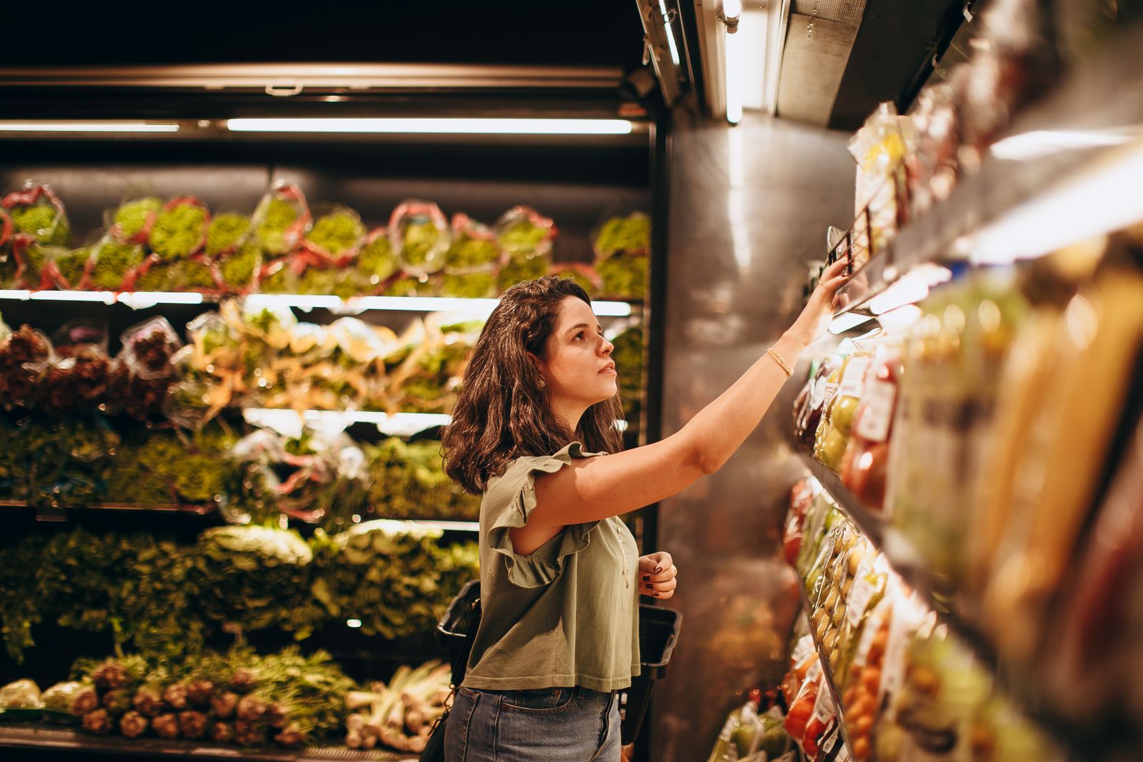 A shopper choosing produce in a bright, modern grocery store