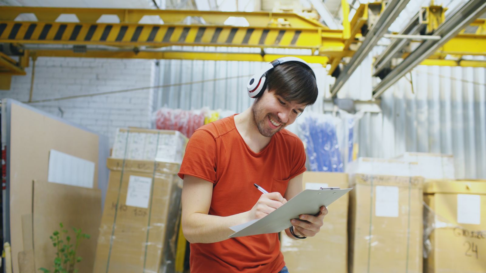 A smiling worker writing on a clipboard while receiving stock