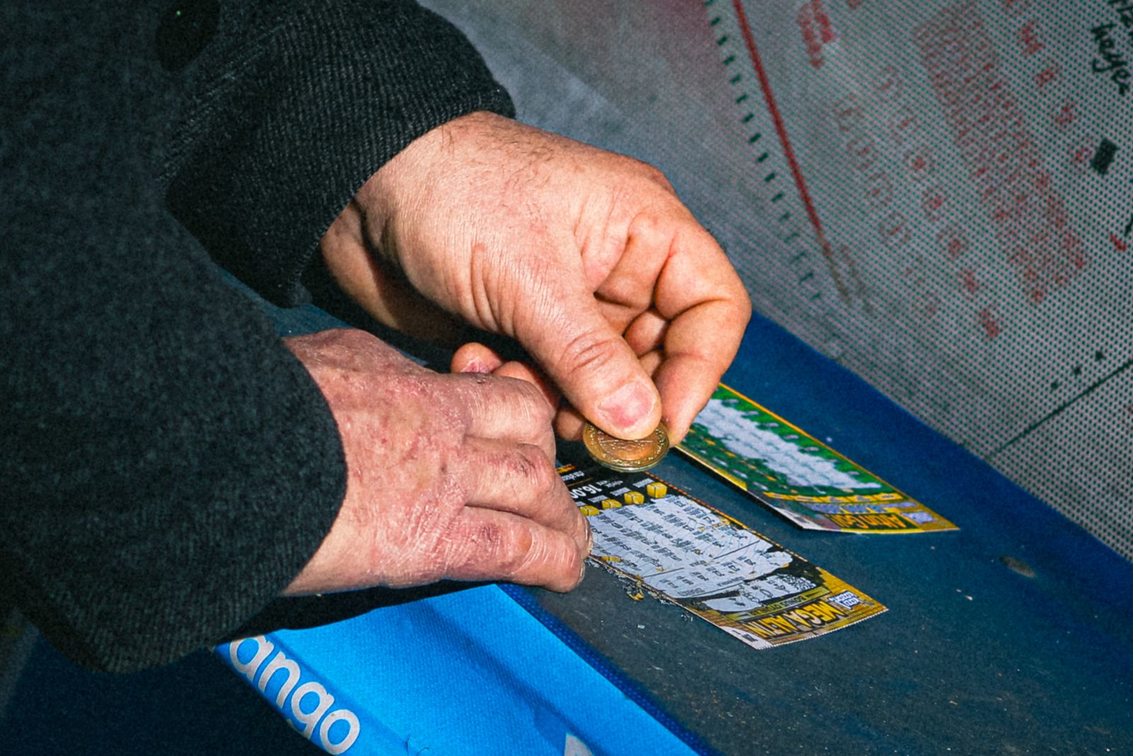 A customer scratching a lottery ticket with a coin on a store counter
