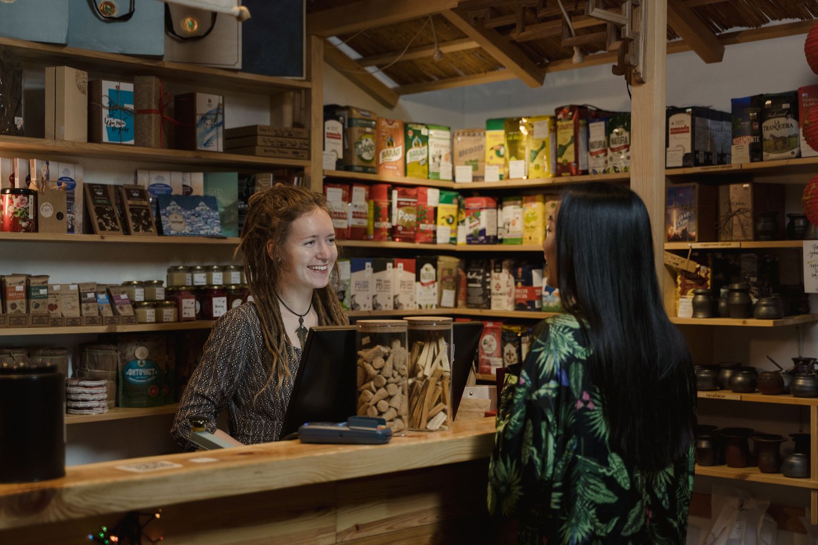 A shopkeeper helping a customer at the counter of a well stocked store