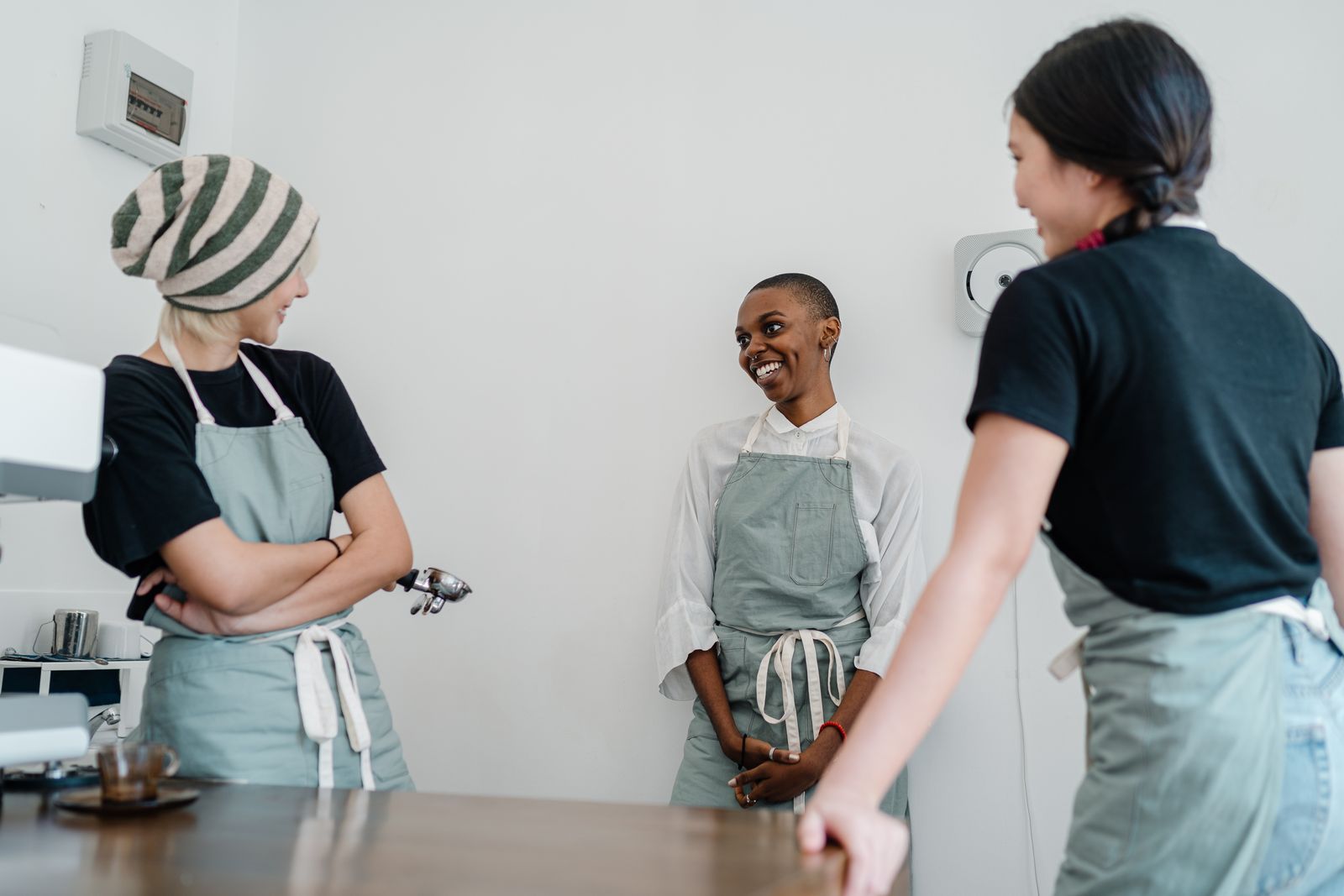 Three colleagues in aprons chatting and laughing behind the counter