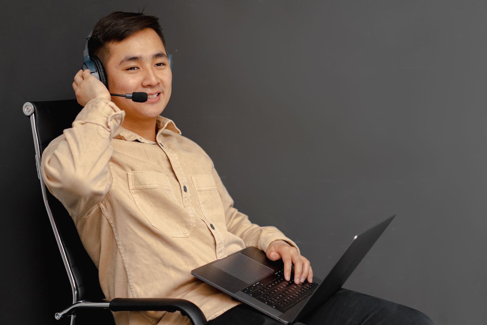A smiling support agent on a headset at a laptop