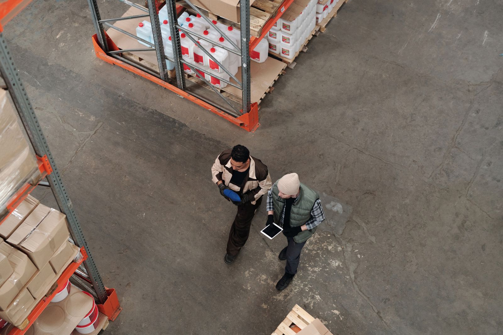 Two workers going over inventory on a tablet, seen from above